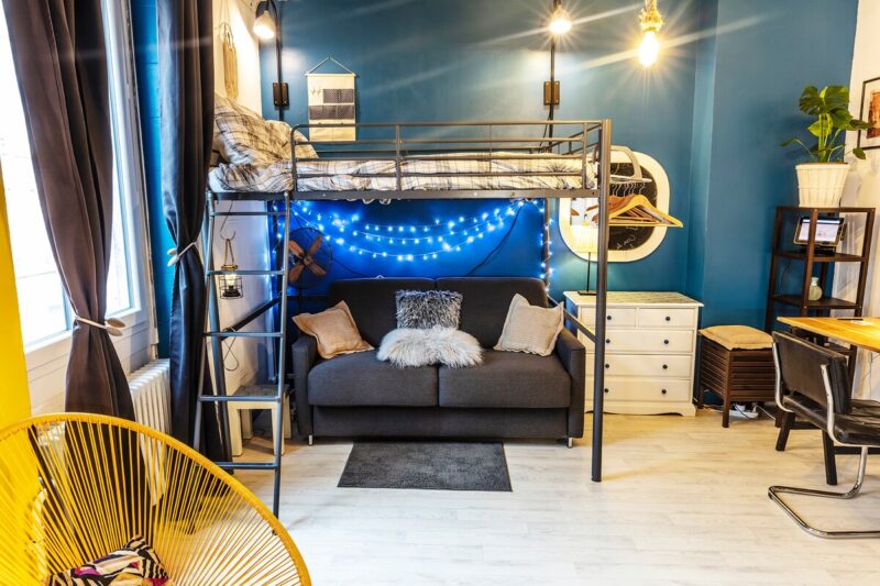 Loft L'Atelier : canapé convertible sous le lit mezzanine, fauteuils jaunes et mur bleu